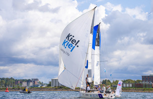 Segelboot mit Kiel.Sailing.City-Logo auf der Förde