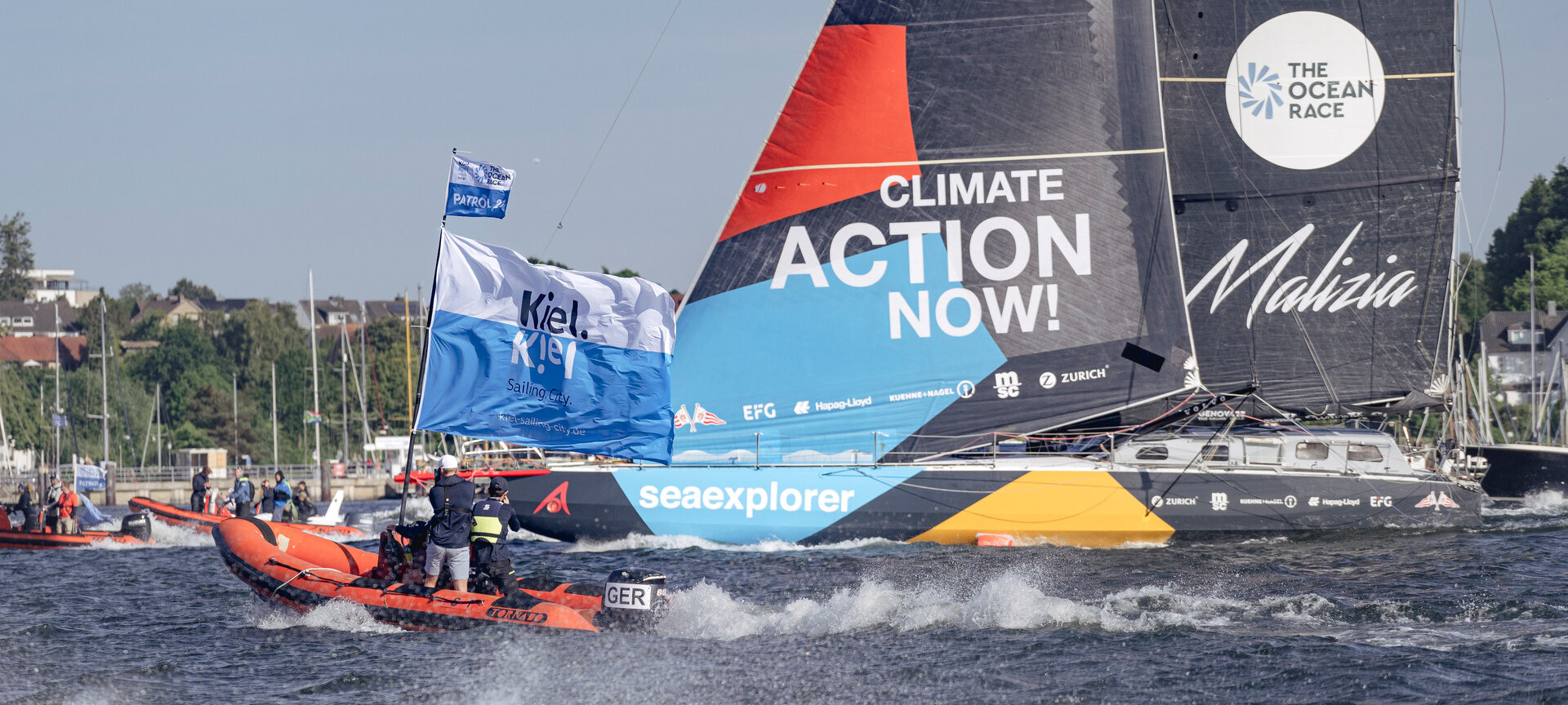 RIB mit Kiel-Marketing Flagge und IMOCA von Team Malizia auf der Kieler Förde