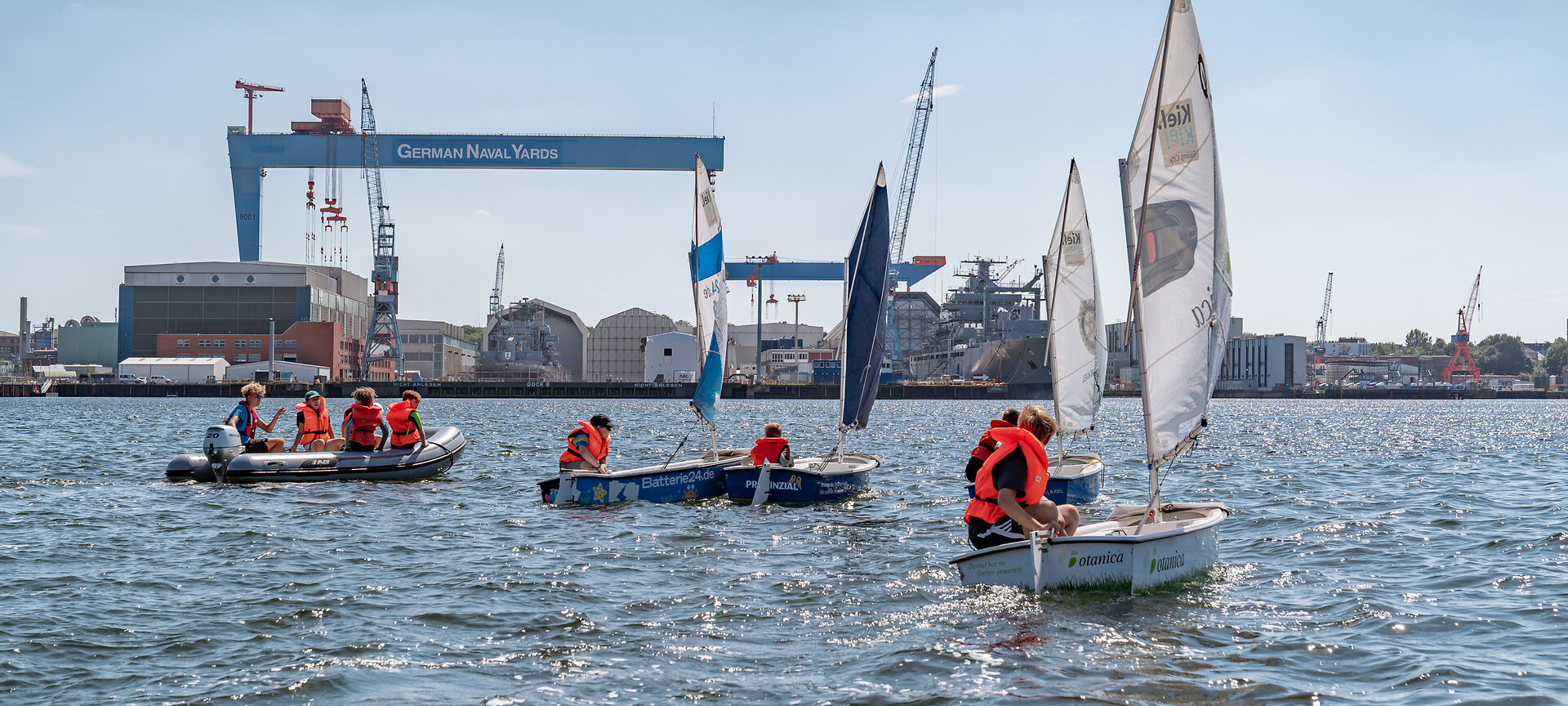 Vier Optis und ein Motorboot auf der Kieler Förde, Kran im Hintergrund